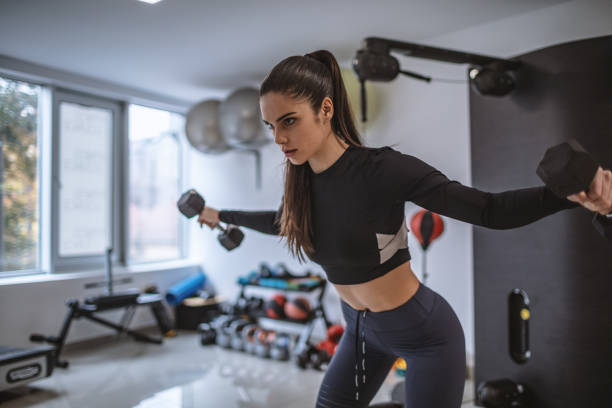 fit joven mujer levantando pesas en el gimnasio - human muscle body building exercising black and white fotografías e imágenes de stock