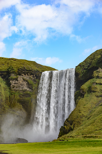 Skogafoss waterfall in Iceland on a summer's day with a blue sky above. The Skógafoss Waterfall is one of Iceland’s hot spots and populair amongst tourist traveling in South Central Iceland.