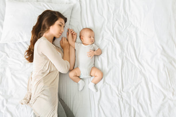 istock Tired mother sleeping in bed with baby by her side 1187340692