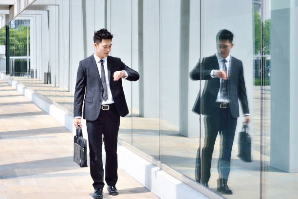 istock One Asian Men Looking at Watch and Walking in Bright Aisle 1187341730