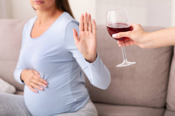 femme enceinte méconnaissable gestring stop to glass of wine indoor - abdomen addiction adult alcohol photos et images de collection