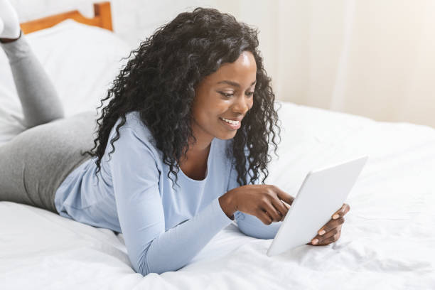 istock Girl reading blog on digital tablet in bed, touching screen 1187342920