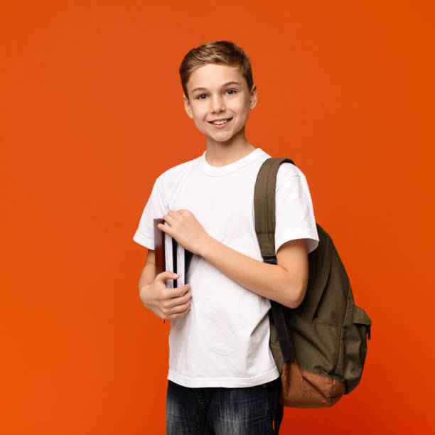 Teen boy ready for getting education, smiling with books and backpack Cute student. Teen boy ready for getting education, smiling with books and backpack, orange background schoolboy stock pictures, royalty-free photos & images