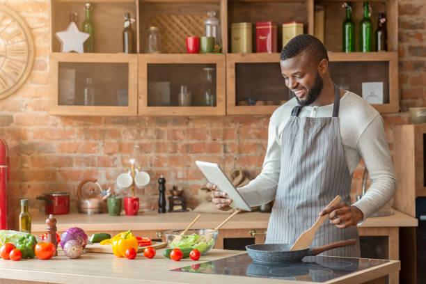 istock Man preparing fresh healthy salad at kitchen, using digital tablet 1187344865