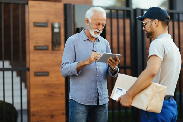 istock Happy senior man signing on touchpad for delivery from a courier. 1187346562