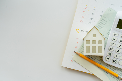 close up top view group of calculator , home model ,yellow pencil, banking account book and calendar on white color background with space for money management ,home loan and personal financial concept