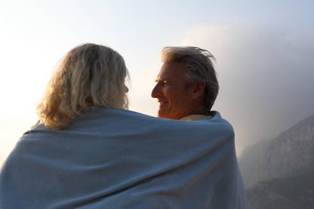 istock Couple walks down beach under blanket at sunrise 1187347032