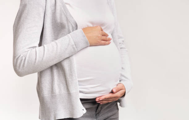 istock Unrecognizable Pregnant Lady Touching Belly Standing Over White Background, Cropped 1187347898