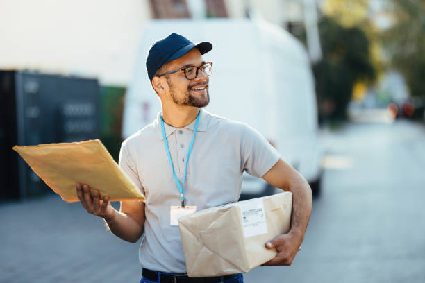 istock Happy courier looking for right address while making home delivery. 1187347908