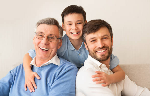 istock Boy Hugging Father And Grandfather Smiling At Camera At Home 1187348095