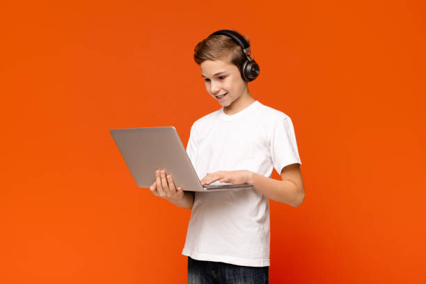 adolescente in cuffia che gioca a videogiochi su laptop - teenager video game gamer child foto e immagini stock