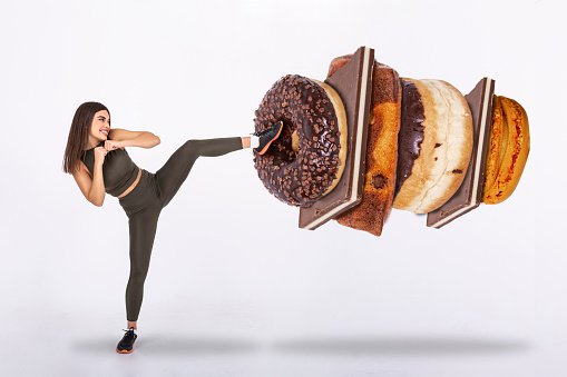 Fit young woman fighting off sweets and candy, Fit young woman saying NO to unhealthy carbohydrates