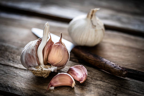 Close up view of a garlic bulb and cloves shot on rustic wooden table. Selective focus. Predominant color is brown. XXXL 42Mp studio photo taken with Sony A7rii and Sony FE 90mm f2.8 macro G OSS lens