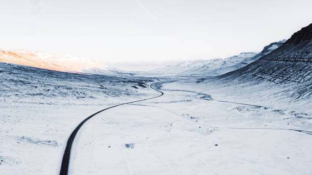 luftaufnahme der schönen winterstraße und der berge bei sonnenuntergang in nordisland - snow winter mountain horizon over land stock-fotos und bilder