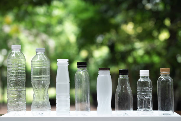 Many different shape bottles arrange into line with blur green garden background, re use container, eco friendly concept, copy space stock photo