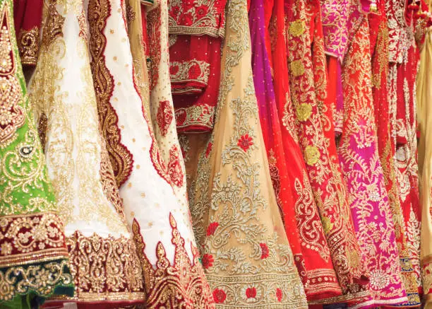 Various colorful shinny Indian bridal weeding dress in a shop. Female party clothes.