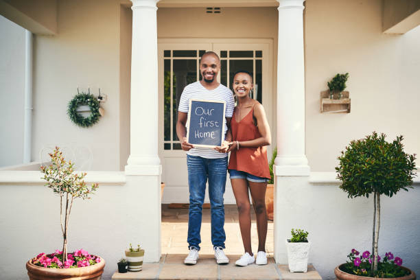 We're so proud to have a place to call our own Portrait of a young couple holding a chalkboard with "our first home" written on it new home stock pictures, royalty-free photos & images