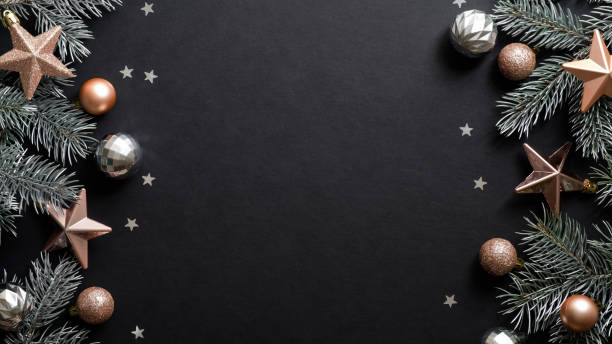 istock Christmas frame. Black Xmas background with pine tree branches, copper color stars, balls, confetti. Christmas frame, greeting card template, web banner mockup. Flat lay, top view, copy space 1187357382