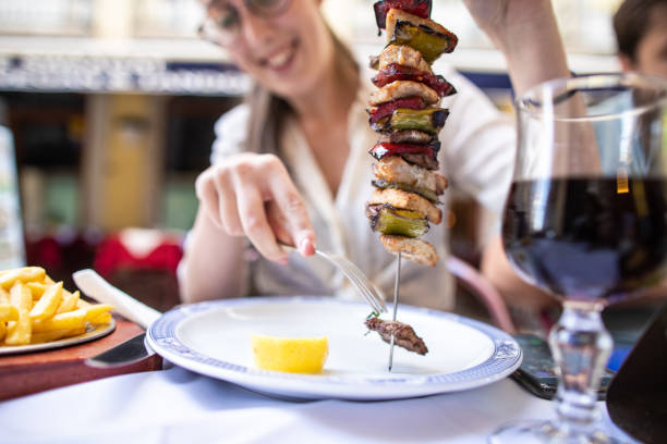 jovem sentada em restaurante ao ar livre e comendo kebab - restaurant chicken roasted spit roasted - fotografias e filmes do acervo