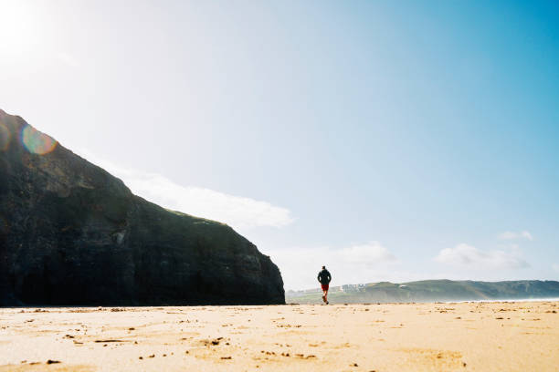istock Man running along Perranporth Beach, Cornwall on a sunny Autumn day. 1187359269
