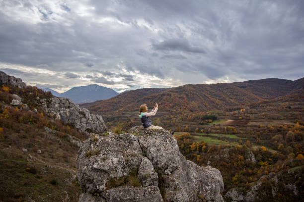 Woman taking selfie on the top of the mountain.