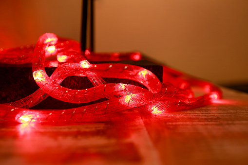 Bright red New Years and Christmas rice lights, shallow depth of field. Abstract red light background. Decorative flashing lights, ornaments to christmas celebration, holiday scene. Christmas concept.