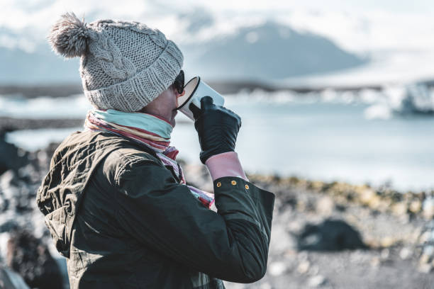 A girl is drinking from a white metal mug