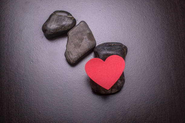 istock Heart love on the hard rocks which it is resting on with dark backgound . 1187365610