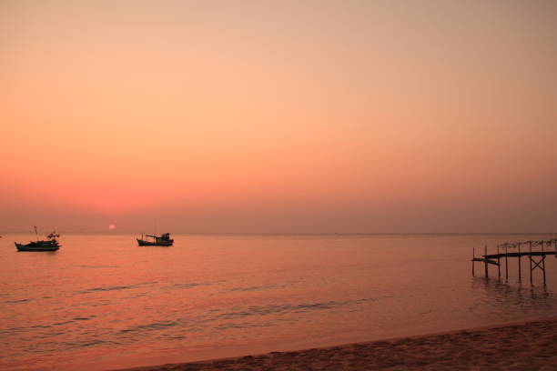 Coucher du soleil rose à la plage avec le bateau et la jetée - Photo