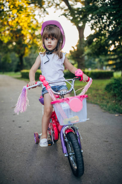 istock Cute girl riding bicycle in park 1187366252