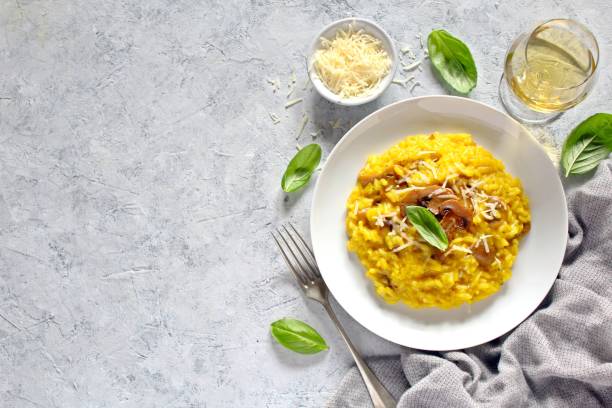 tradycyjne włoskie risotto z grzybami, szafranem i parmezanem podawane z białym winem. - parmesan cheese risotto rice basil zdjęcia i obrazy z banku zdjęć
