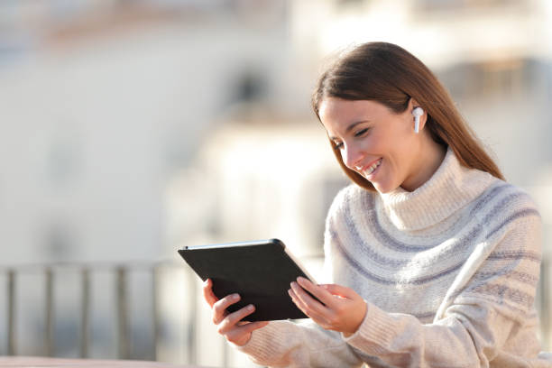 istock Happy woman watching media on tablet in a balcony 1187366435