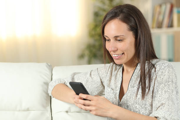 istock Happy woman uses smart phone on a couch at home 1187367229