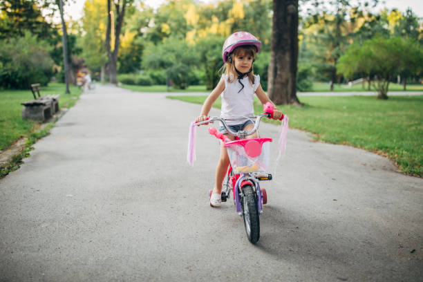 istock Beautiful little girl riding bicycle in park alone 1187367272