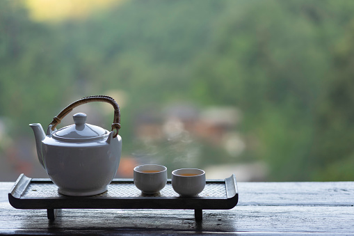Hot tea in teapot and cup on wood table nature view.