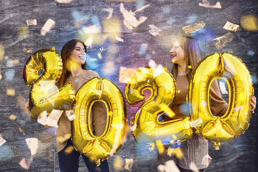 New year celebration concept. Two beautiful women with golden air balloons 2020