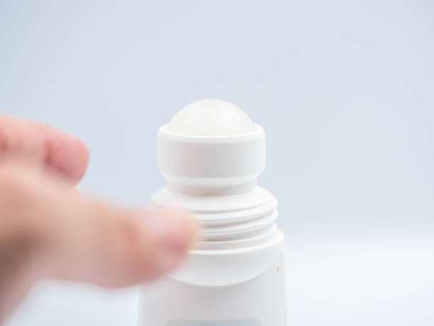 Closeup of Roll-on deodorant with gray background in the bathroom and blurry woman 's hand. stock photo