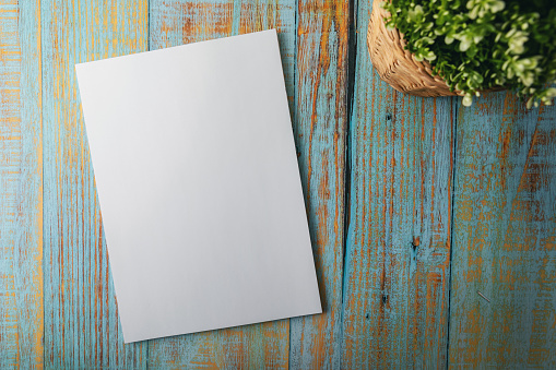 blank A4 brochure mockup on blue wooden background. top view