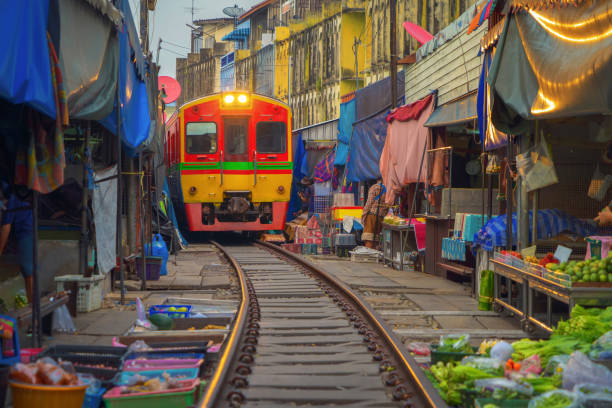 Rom Hoop market. Thai Railway with a local train run through Mae Klong Market in Samut Songkhram Province, Thailand. Tourist attraction in travel and transportation concept. Rom Hoop market. Thai Railway with a local train run through Mae Klong Market in Samut Songkhram Province, Thailand. Tourist attraction in travel and transportation concept. experiential travel stock pictures, royalty-free photos & images