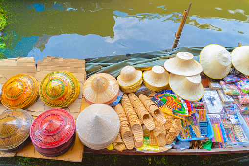 Local people sell fruits, food and souvenirs on boats at Damnoen Saduak Floating Market in Ratchaburi District, Thailand. Famous Asian tourist attraction.