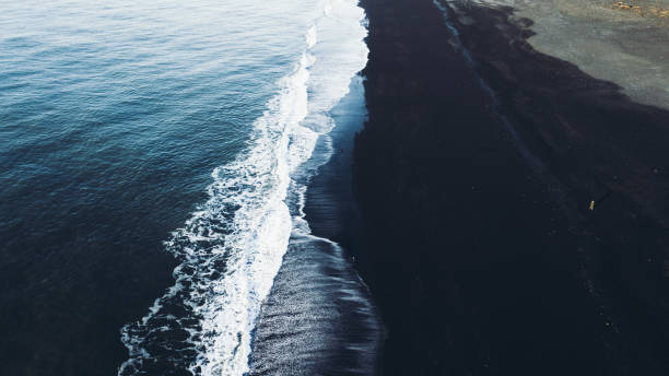 Aerial view of tourist walking at the black sand beach in Iceland Drone photo of man enjoying morning at beautiful Reynisfjara beach in Vik, South Iceland - feeling freedom golden circle route photos stock pictures, royalty-free photos & images