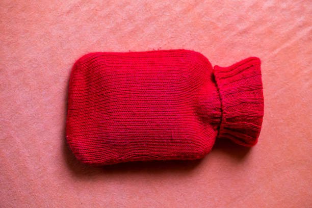 red knit hot water bottle  on pink background.