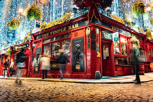 The Temple Bar pub in Dublin city centre, popular tourist attraction with christmas lighting and decorations, shot at night with blurred people in long exposure with retro vintage colour grading