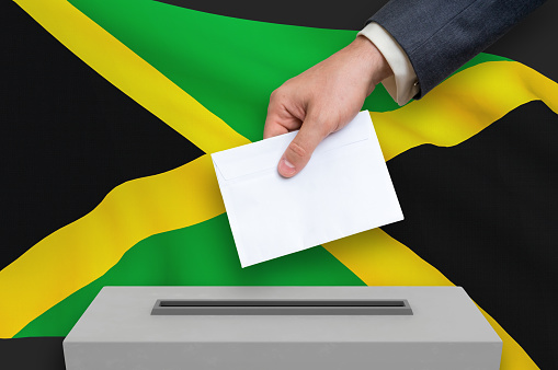 Election in Jamaica - voting at the ballot box. The hand of man is putting his vote in the ballot box. 3D rendered illustration.
