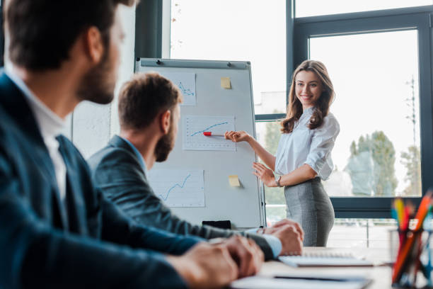 istock selective focus of beautiful speaker smiling while looking at businessmen in office 1187392169