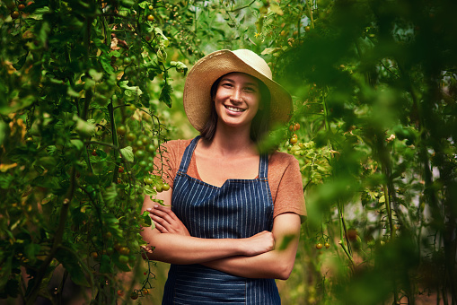 Portrait of an attractive young female farmer posing with her arms folded outdoors in the fields at her farm