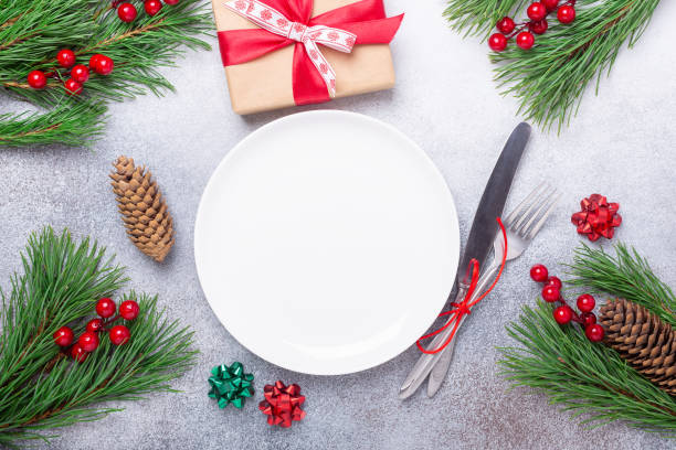 istock Christmas table place setting with empty white plate, gift box, cutlery with festive decorations on stone background 1187398706