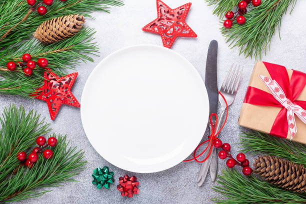 istock Christmas table place setting with empty white plate, gift box, cutlery with festive decorations on stone background 1187398730