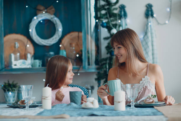 istock Mother with a little daughter sit and have breakfast at table in  kitchen. 1187399246