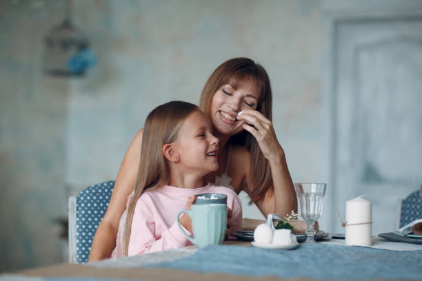 istock Mother with a little daughter sit and have breakfast at table in  kitchen. 1187399291